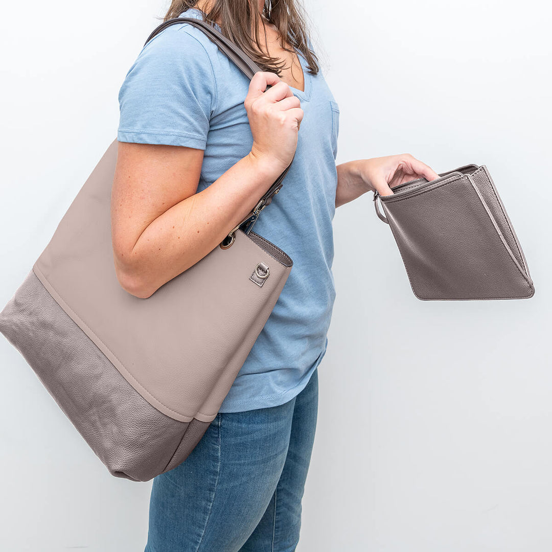 Lady carrying a Gisele handbag with wristlet#colour_bronzebge
