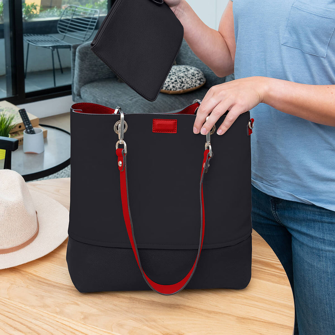 Lady placing a zippered pouch into a vegan leather black Gisele handbag#colour_scarletblk